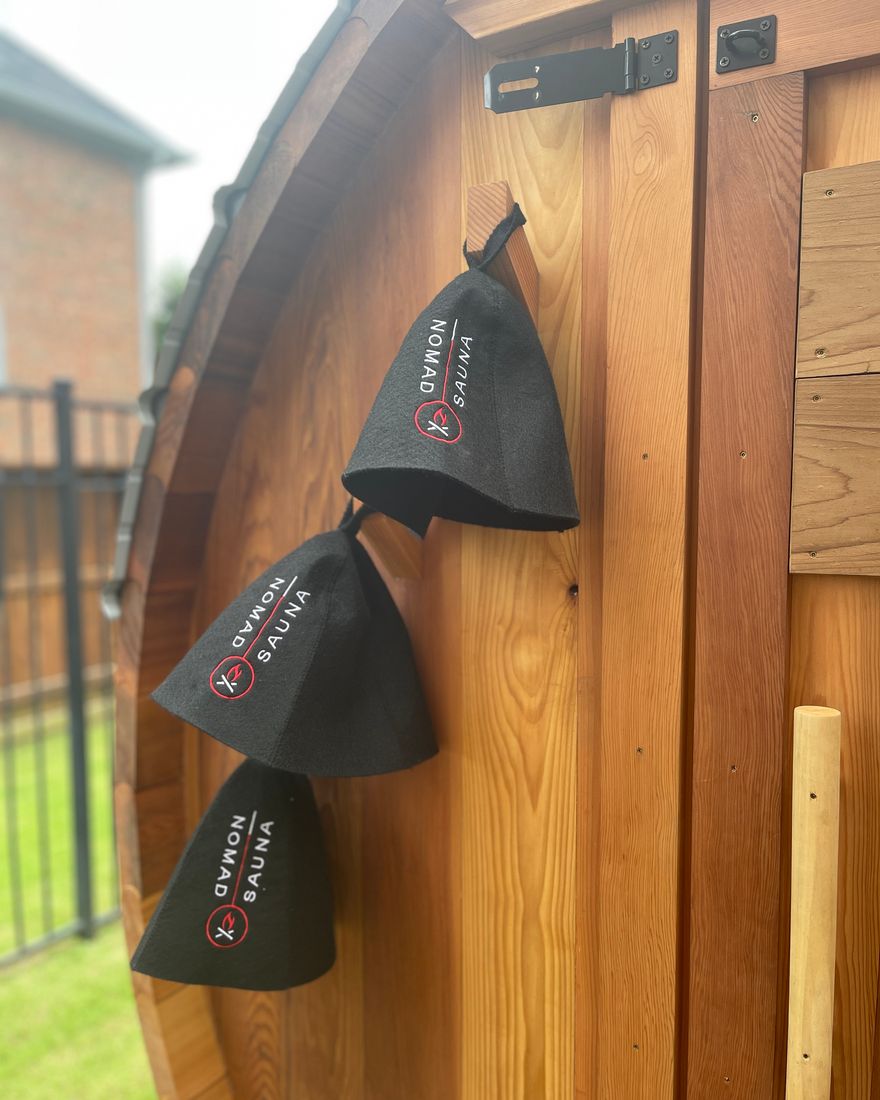 Wool sauna hats hanging on the cedar exterior