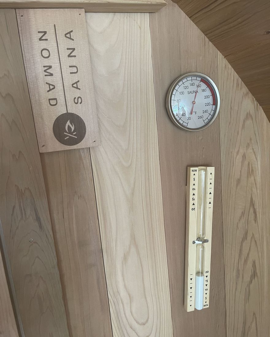 Nomad Sauna plaque, thermometer and hourglass on the cedar wall