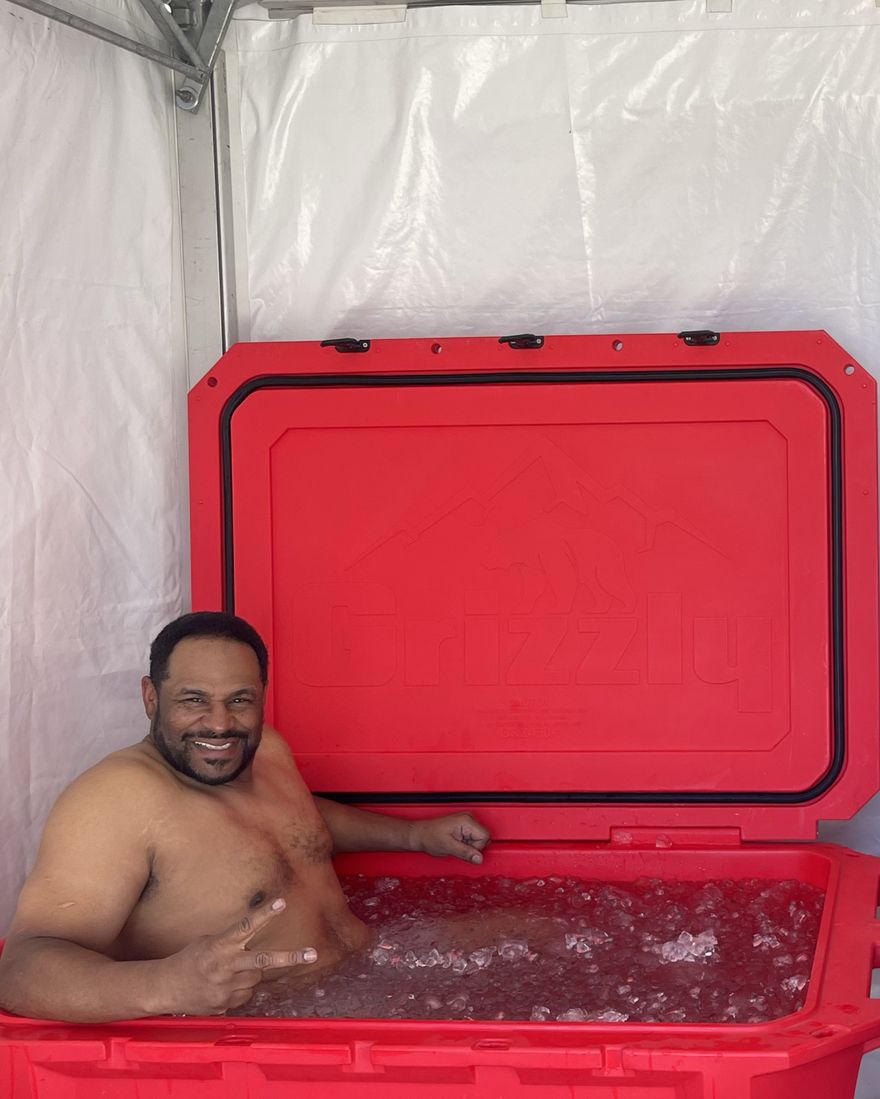 A guest in the cold plunge under an event tent